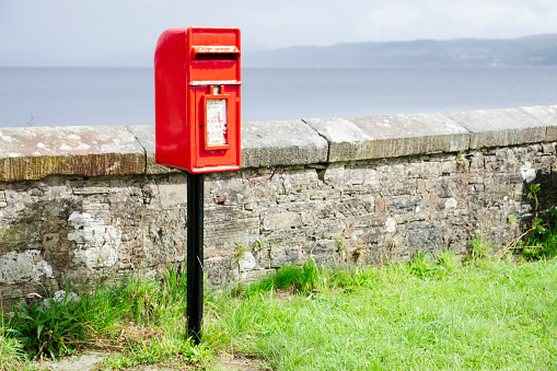 Red post box in Scottish rural location brightly lit under dark sky uk