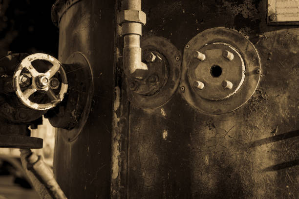 Grungy old steel boiler of steam engine with fittings and valve close up.
