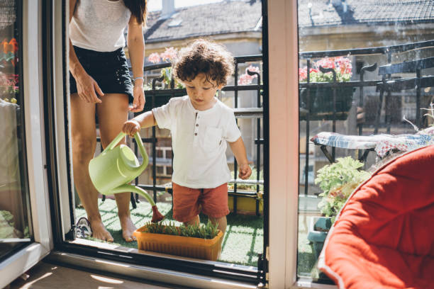 istock Little boy watering flower plants with his mother 1021308366
