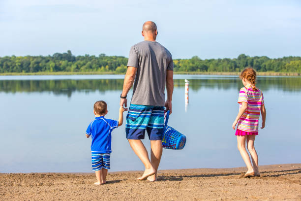 istock Father & Two Children Walking Towards Water At Beach 1021321012