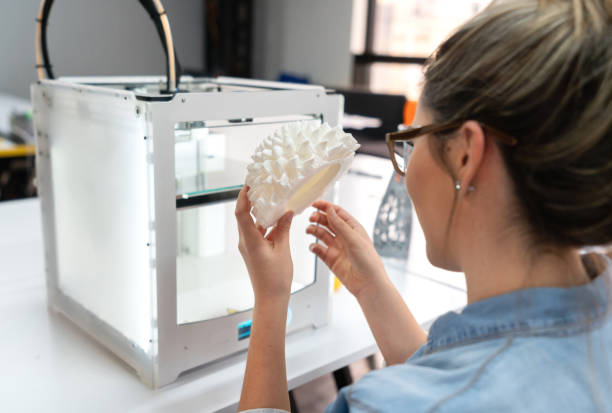Woman using a 3D printer Portrait of a woman using a 3D printer at a workshop - technology concepts 3d printing photos stock pictures, royalty-free photos & images