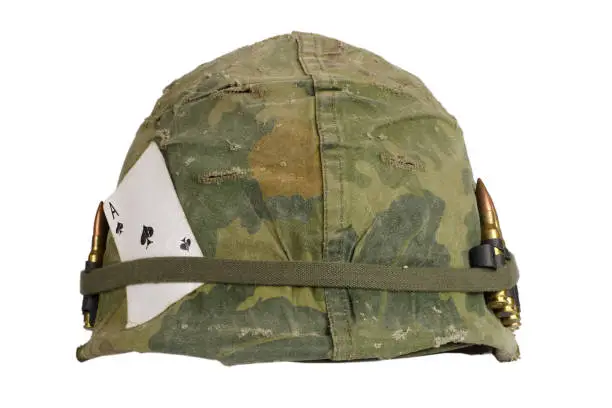 Photo of US Army helmet Vietnam war period with camouflage cover and ammo belt and amulet - the ace of spades playing card