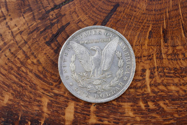 istock antique silver dollar on wooden background 1021359160