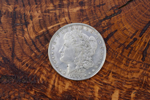 istock antique silver dollar on wooden background 1021359166
