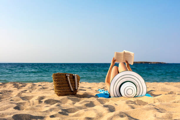 istock woman is reading book on beach 1021372514
