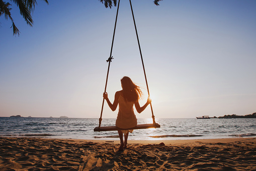 happy summer beach holidays, beautiful girl relaxing on swing at sunny sunset, enjoy travel vacation at sea, happiness concept