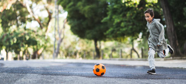 Boy play with football ball park