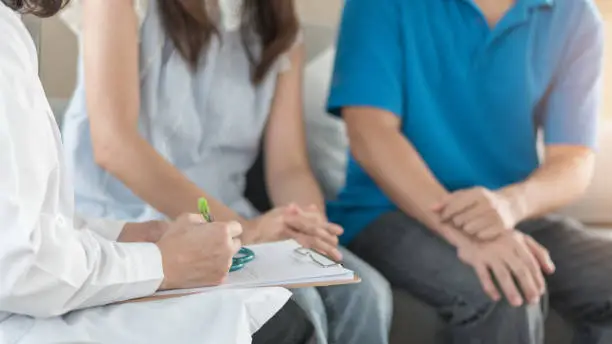 Photo of Doctor or psychologist with patient couple consulting on marriage counseling, family medical healthcare therapy, fertility treatment for infertility, or psychotherapy session concept