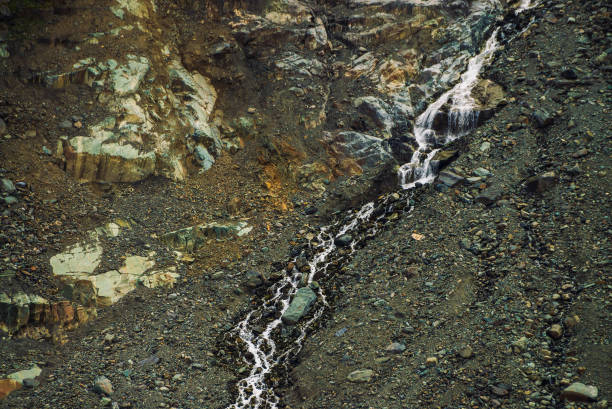 texture naturelle détaillée de pente de pierrailles. jet d’eau de montagne descend à flanc de montagne. petite chute d’eau sur la roche. paysages insolites de la nature majestueuse. - waterfall rock mountain bright photos et images de collection