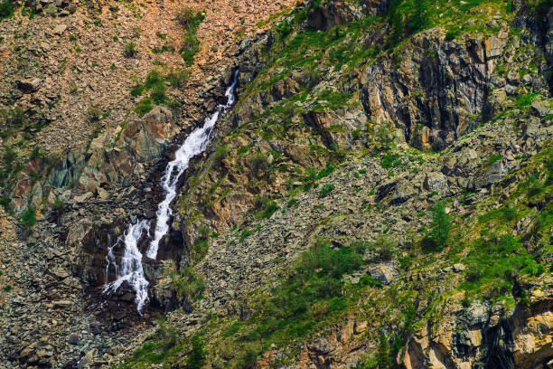 texture naturelle détaillée de pente de pierrailles. jet d’eau de montagne descend à flanc de montagne. petite chute d’eau sur la roche avec la végétation. paysages insolites de la nature majestueuse. - waterfall rock mountain bright photos et images de collection