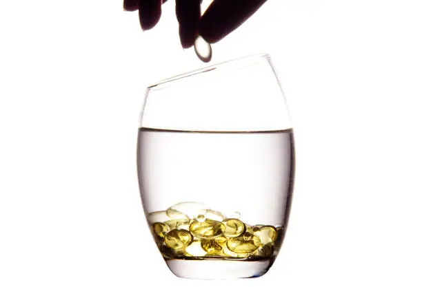 pills and water glass in front of white background