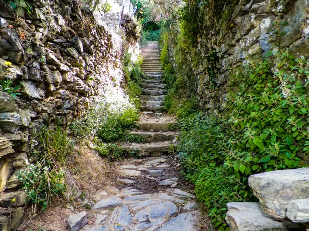 Old stairway and narrow rock walls heading up to a mountain trail between towns in Manarola Italy