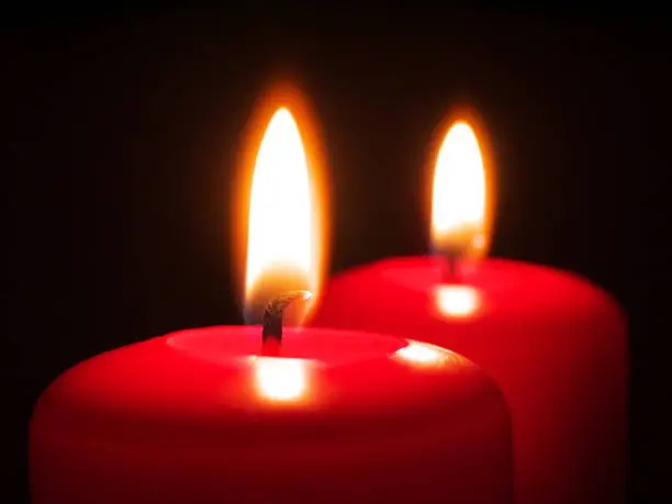 two red burning candles, shallow depth of field, focus on candlewick, macro