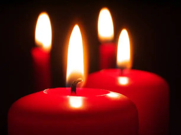 four red burning candles, shallow depth of field, focus on candlewick, macro