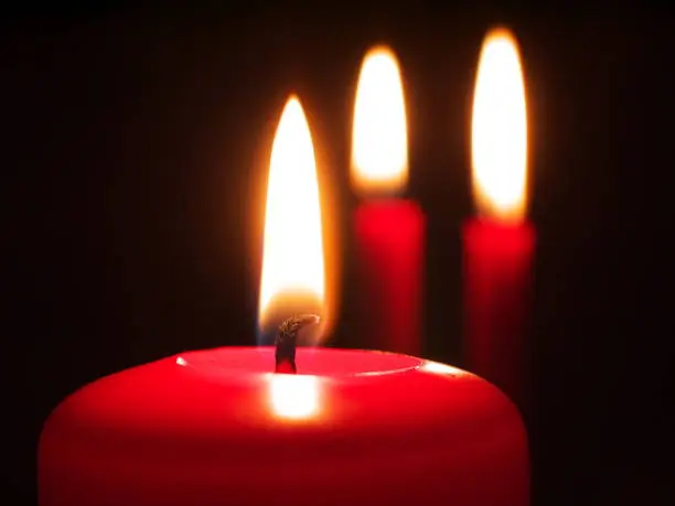 three red burning candles, shallow depth of field, focus on candlewick, macro