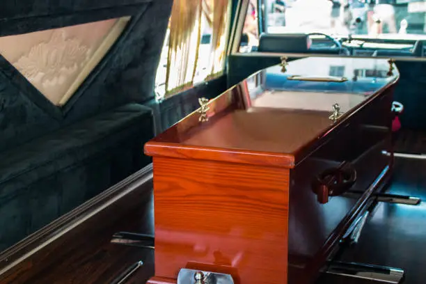 A wooden coffin in the back of a hearse.