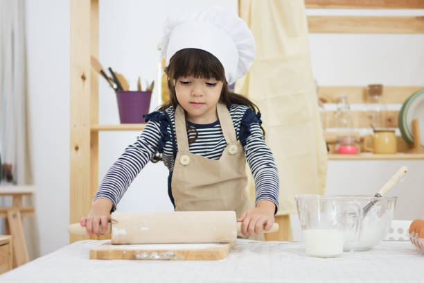 istock Child in a cook clothes breaks an egg in a bowl on a table 1021500214