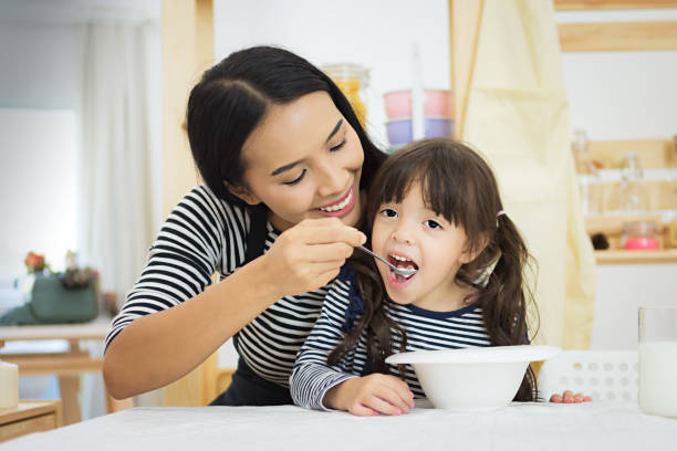 mother and daughter having healthy breakfast in kitchen - family mother domestic life food imagens e fotografias de stock