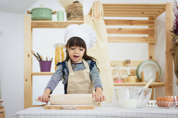 istock Child in a cook clothes breaks an egg in a bowl on a table 1021500246