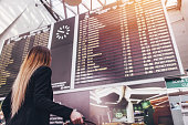 Young woman standing against flight scoreboard in airport