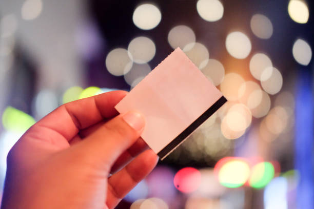 istock Young man's hand holding a paper ticket on blurred background (booking ticket concept) 1021513262