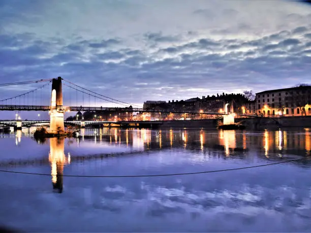 The Rhone, a river, in the city of Lyon in France By night. There is a bridge and some facade of houses