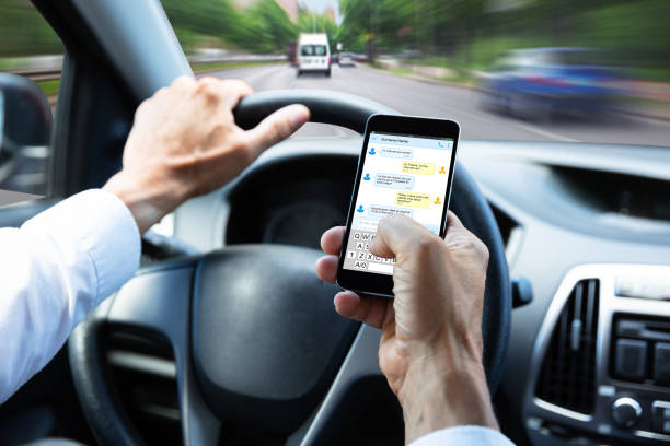 man typing text message on mobile phone while driving car - conduzir imagens e fotografias de stock