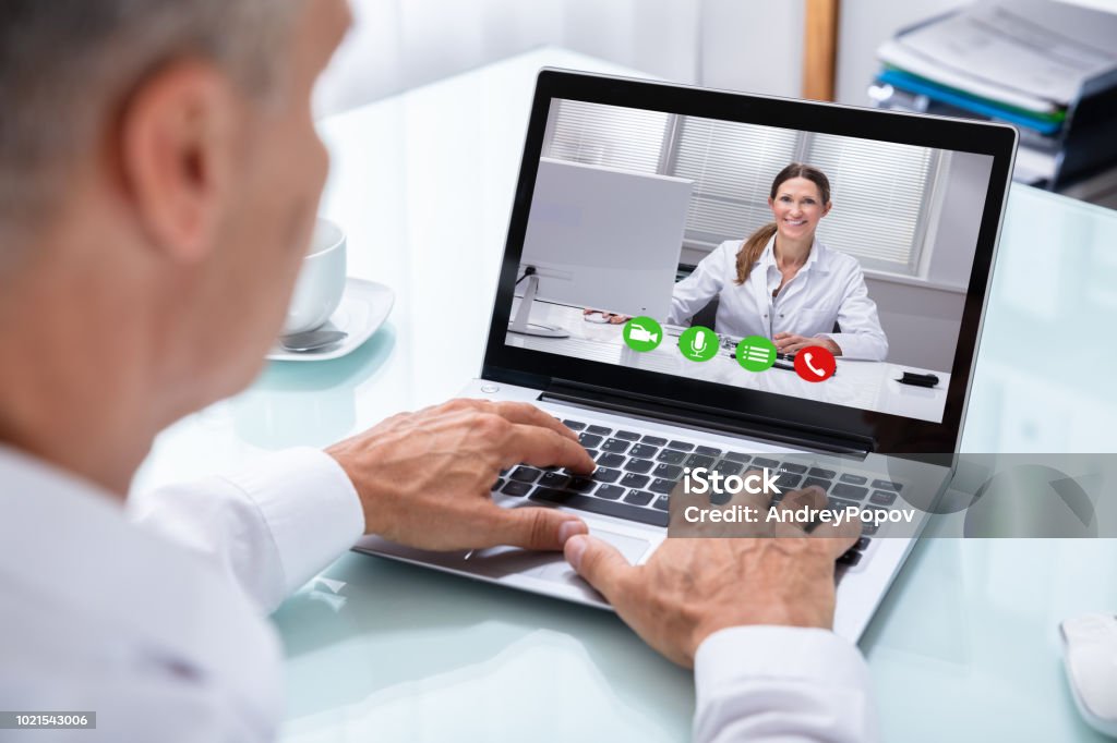 Videoconferencia de empresario con médico en portátil - Foto de stock de Doctor libre de derechos