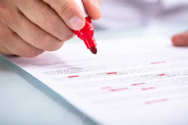 Close-up Of A Businessperson's Hand Holding Marker On Document