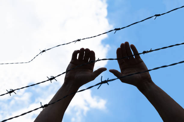 istock Refugee Holding Barbed Wire Fence 1021543298