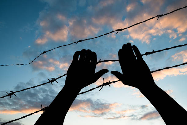 istock Refugee Holding Barbed Wire Fence 1021543308