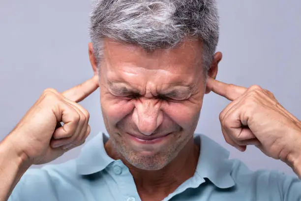 Close-up Of A Mature Man Covering His Ears With Fingers