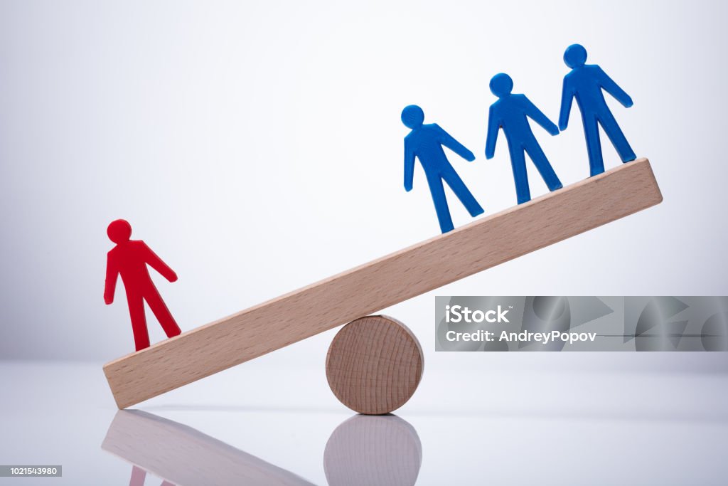 Red Human Figure Standing Against Team On Seesaw Red Human Figure Standing Against Blue Team On Wooden Seesaw Imbalance Stock Photo