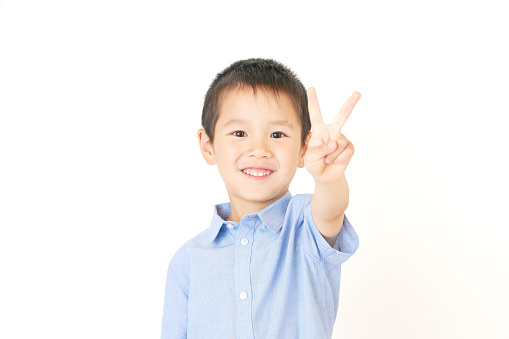 smiling Asian boy peace sign gesture