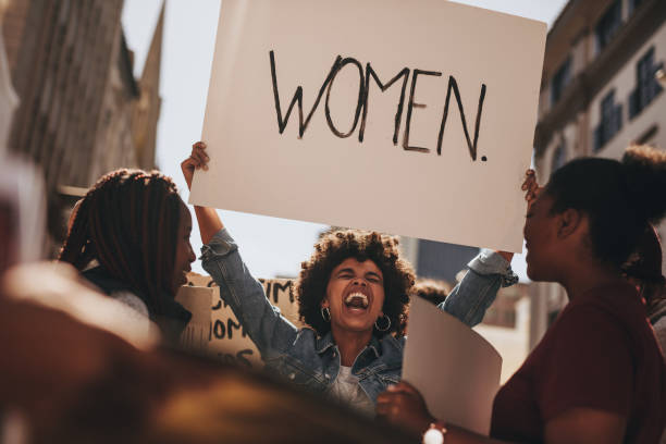 Group of female demonstrating outdoors African woman holding a banner and laughing during women march. Group of female demonstrating outdoors with placards. womens rights photos stock pictures, royalty-free photos & images