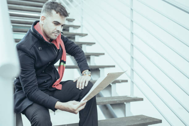 istock Concentrated young man reading papers on stairs 1021568712