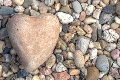 A heart made of stone or terracotta. Background with colorful pebbles.