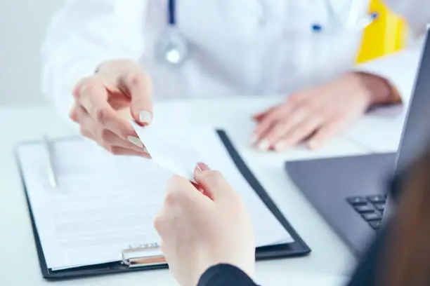 Photo of Female physician hand give white blank calling card to businesswoman closeup in office