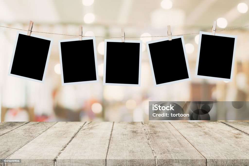 Empty wood table and instant photo hanging on blur image background of people display montage for product. Instant Print Transfer Stock Photo