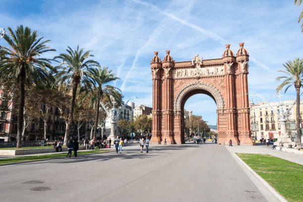 Arc de Triomf at Barcelona Barcelona, Spain - November 13, 2010: Tourists walking near ''Arc de Triomf''. The Arc de Triomf is adorned with some distinctive sculptures. Josep ReynAs designed a frieze on the front titled, Barcelona welcomes the nations depicting Spains provinces with a decorative coat of arms set off by two lions. The front of the arch is also noteworthy for its use of twin columns that deviate from the pure MudAjar style.' arc de triomf barcelona stock pictures, royalty-free photos & images