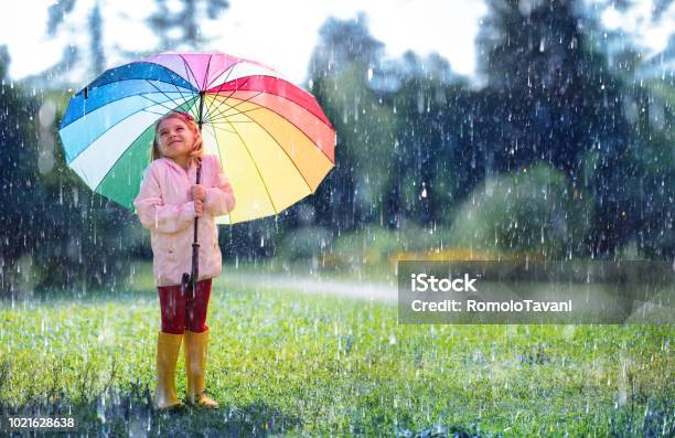 Happy Child With Rainbow Umbrella Under Rain Stock Photo - Download Image Now - Rain, Child, Umbrella