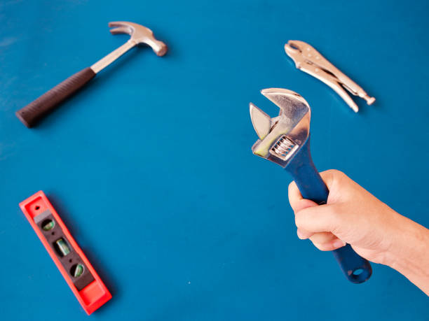 istock Hand holding adjustable wrench, background is variety handy tools on blue wooden, with copy space for text,craftsman tools,Labor day and Hardware store concept 1021640836