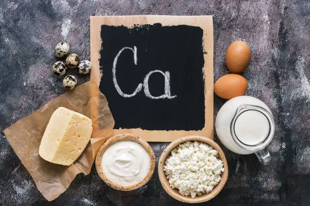 Photo of Dairy products rich in calcium on a rustic background. Signboard with text. Flat lay, copy space.