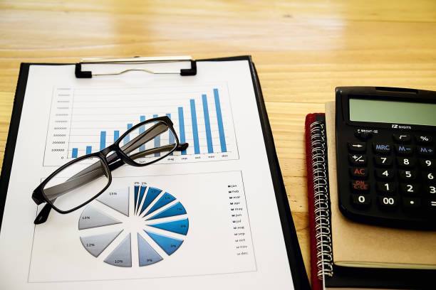 istock business concept : financial graph and chart report with pen, graph with notebook, glasses and calculator on desk of financial advisor. 1021664268