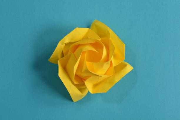 Yellow origami paper flower on blue background