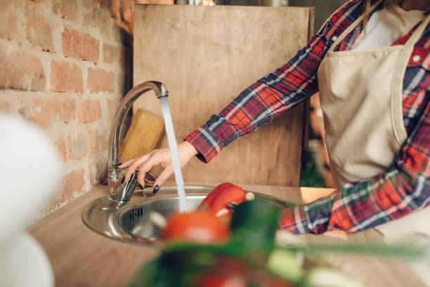 istock Female cook in apron washes fresh vegetables 1021671712