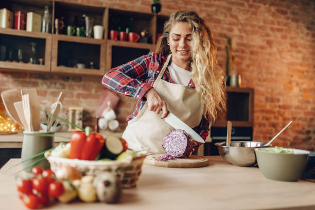 istock Female cook in apron cutting fresh vegetables 1021673796