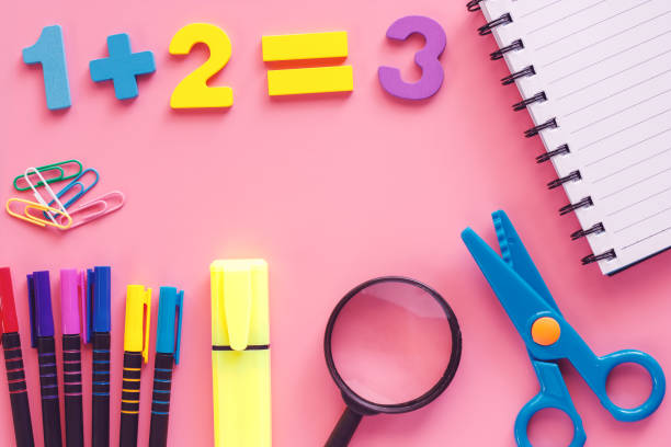 istock Learning supplies with notebook, scissors, magnifying glass, coloured pen, highlighter pen, binder clip and wooden number on pink background for education and back to school concept 1021681088