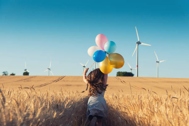 mädchen mit bunten luftballons läuft den weg windenergie - konzepts windenergie - fuel and power generation power wind power supply stock-fotos und bilder