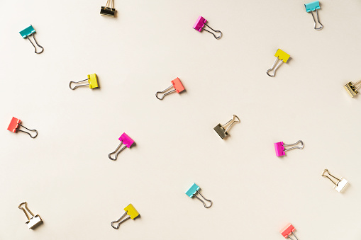 Colorful binder clips on yellow background. Back to school colorful flat lay